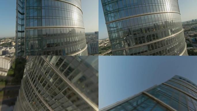 映照蓝天的玻璃摩天大楼。FPV无人机在建筑物上移动