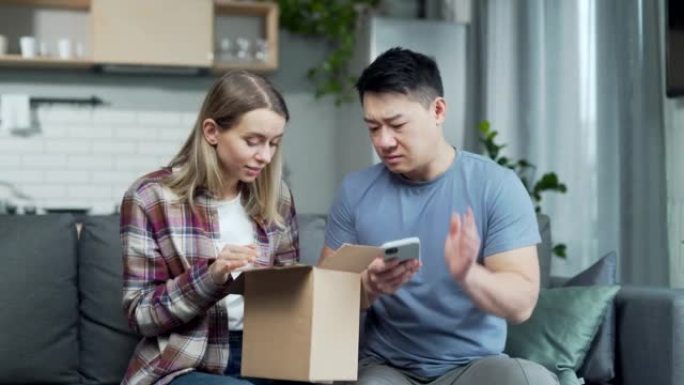 震惊沮丧的夫妇顾客打开纸箱收到错误或损坏的购物订单包裹。悲伤的年轻亚洲男女拆包错误的包裹