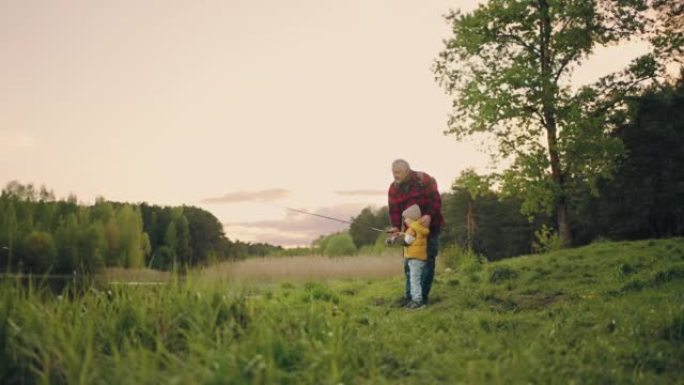 爷爷和孙子一起在湖岸钓鱼，夏天或春天美丽的风景
