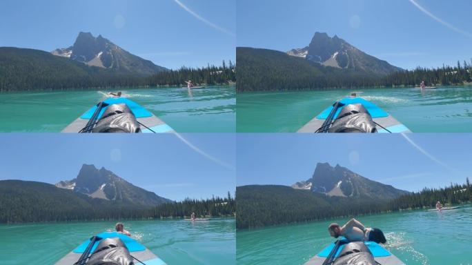 男子在潜水后在宁静的山湖上取回站立的桨板