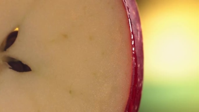 一滴水顺着成熟多汁的红苹果片的表面流下来。慢动作4K