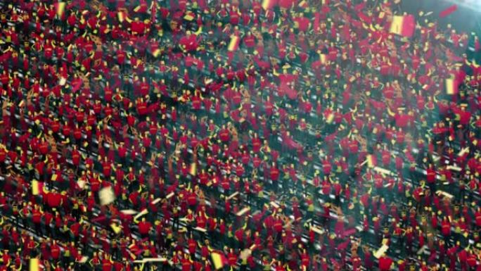 体育场看台上有比利时国旗颜色的人群。激动的足球迷挥舞着旗帜