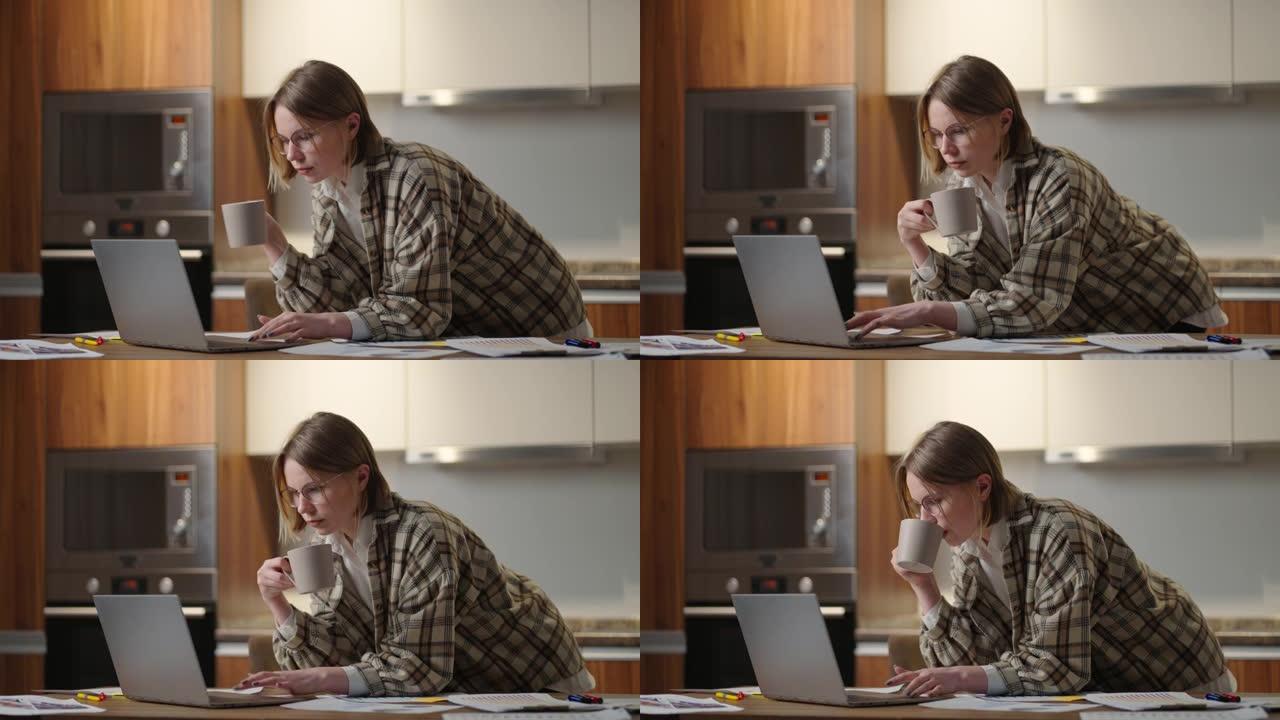 一个女人喝咖啡，看着笔记本电脑看文件
