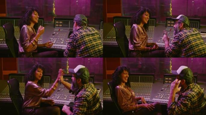 女歌手和她的唱片制作人在录音室的控制室里击掌