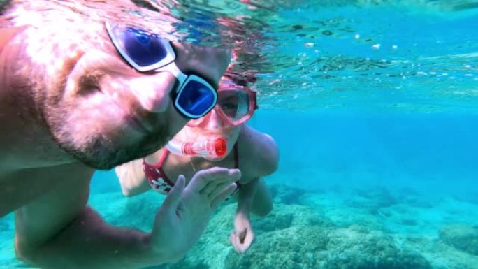 夏天在海里浮潜。夫妇向可穿戴相机挥手。水下射击