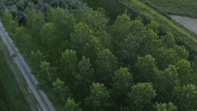 骑自行车的人在日落时沿着砾石路径骑自行车的空中无人机视图