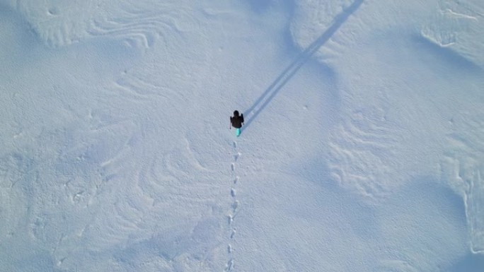 孤独的人走过一片白雪皑皑的田野，空中射击。