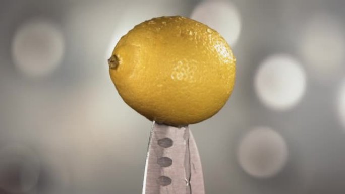 新鲜的柠檬随着水落在刀子上而掉落。白色波克厨房。慢动作。