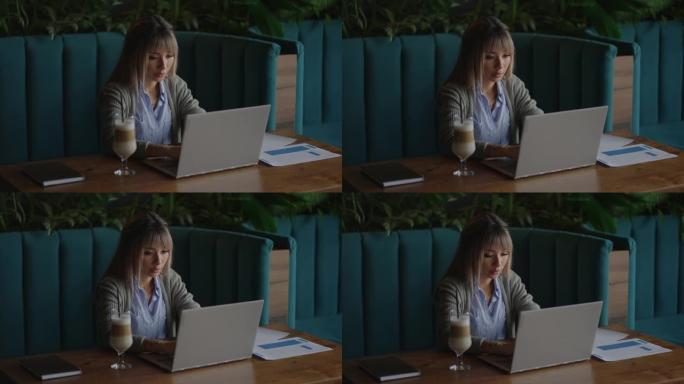 年轻的亚洲漂亮的女办公室职员坐在笔记本电脑在桌子上，工作和思考。