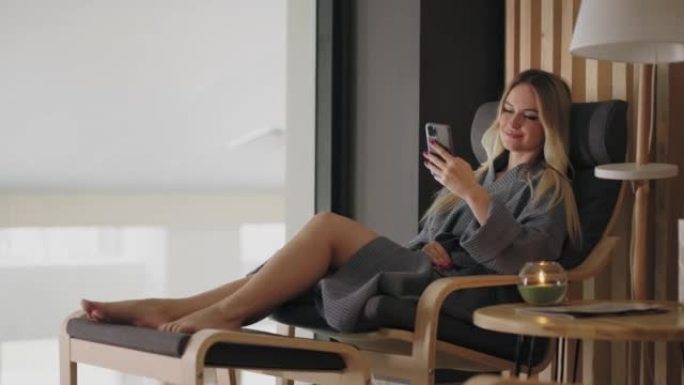 美丽的女人在水疗沙龙放松治疗后，使用智能手机和免费无线网络，浏览社交媒体
