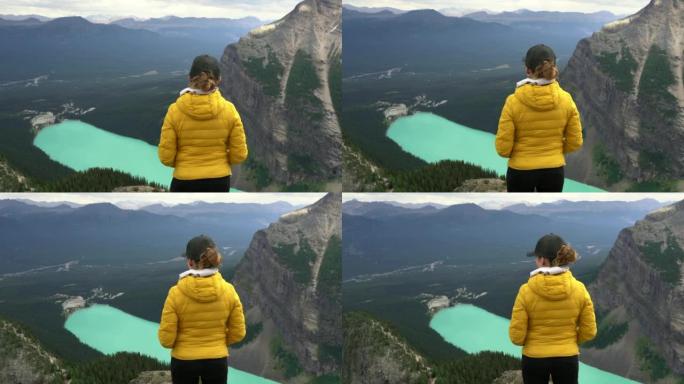 女徒步旅行者在加拿大艾伯塔省班夫国家公园的魔鬼拇指了望台欣赏路易丝湖的景色