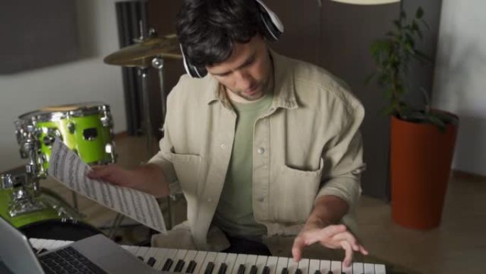 男人通过笔记本电脑弹奏表中的笔记来上钢琴课