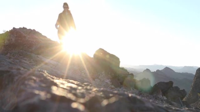 女徒步旅行者沿着山脊到达山顶，日出