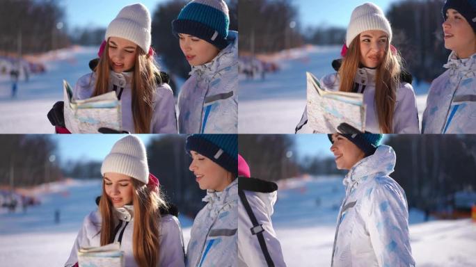 两名年轻妇女使用纸质地图选择路线，离开阳光明媚的滑雪胜地。自信的女性高加索朋友在户外聊天的肖像。