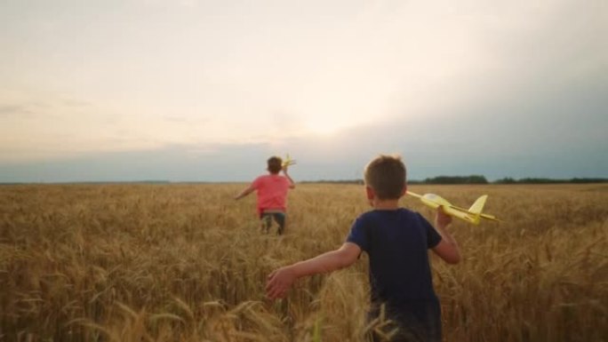 两个小兄弟在金色的黑麦球场上奔跑，玩飞机玩具，男孩的后视