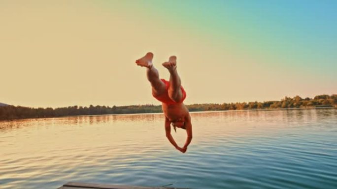 SLO MO TS年轻人在码头上奔跑，日落时跳入湖中