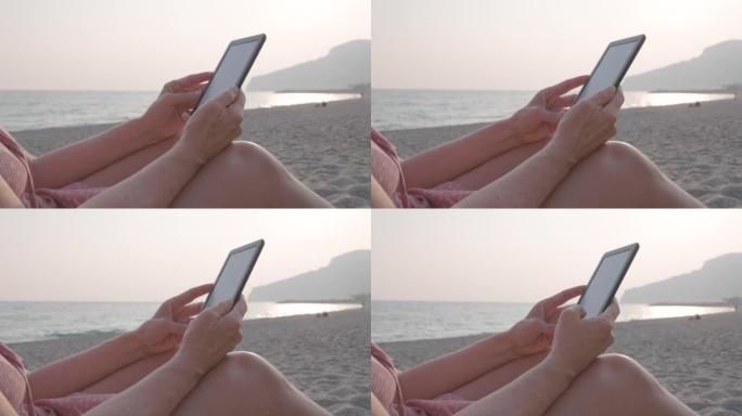 女人在海滩上放松时使用电子阅读器，特写镜头