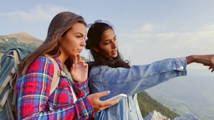 SLO MO两名女徒步旅行者在手机上观看地图时指向远方