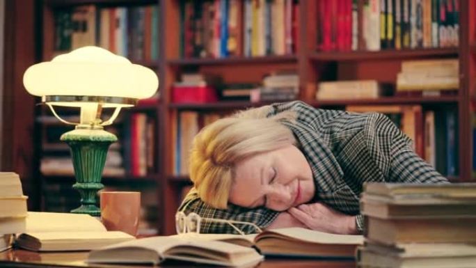 50多岁的疲倦的老师在长时间工作后躺在桌子上看书