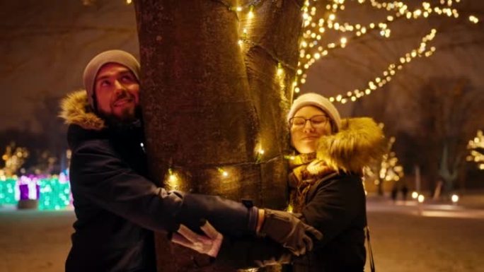 在一个下雪的夜晚，一对夫妇在慢动作中拥抱圣诞树。牵手