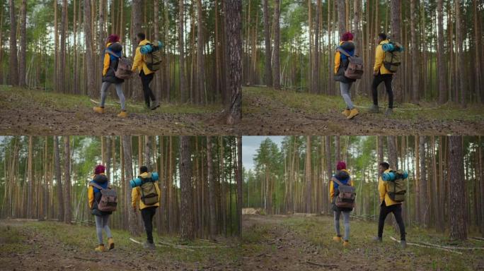 两名非裔美国人旅行徒步旅行者背着背包散步，一边看着森林里的风景。情侣黑人和女人带着手机旅行团队探索野