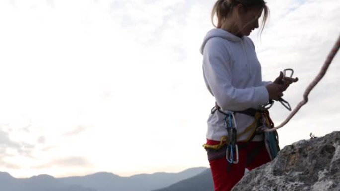 女性攀岩者在攀爬时整理装备，向外看