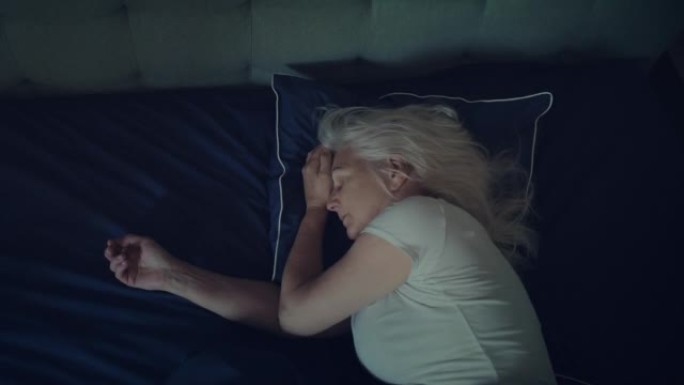 焦虑，成熟的女人试图在晚上睡觉。处理睡眠障碍，双手握着头。延时
