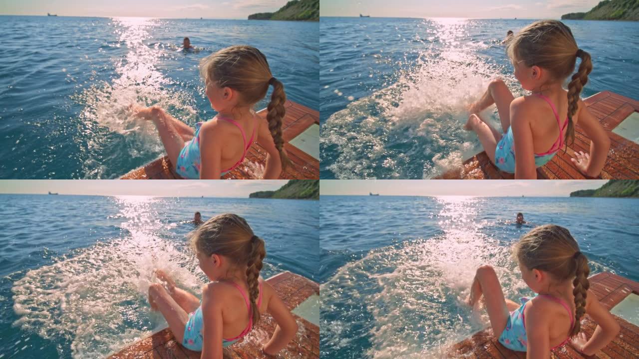 SLO MO小女孩坐在游艇的游泳平台上，双脚晃入水中