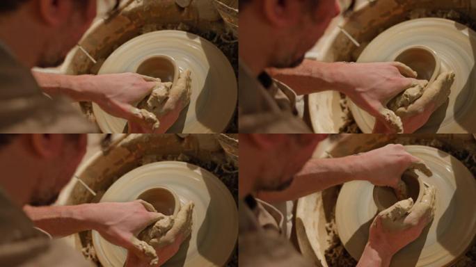 男性陶工将锅底压在陶工的轮子上