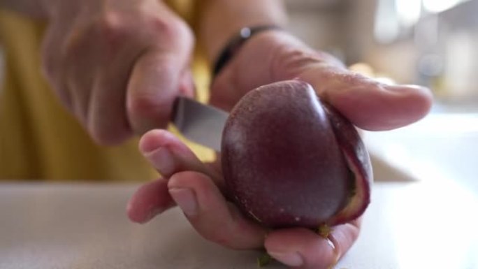 室内用菜刀近距离切割百香果。无法辨认的高加索人表现出健康的维生素热带水果。生活方式和健康饮食。