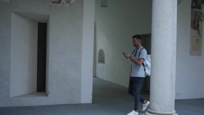 年轻人走过院子里的走廊，用手机阅读