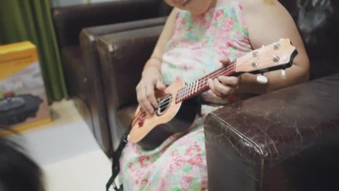 奶奶在家里的客厅里为她蹒跚学步的男孩弹吉他
