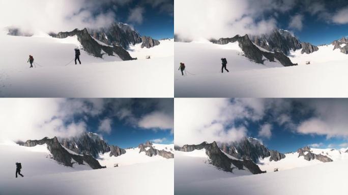 一队登山者沿着欧洲阿尔卑斯山的冰盖斜坡移动。遥远的轮廓