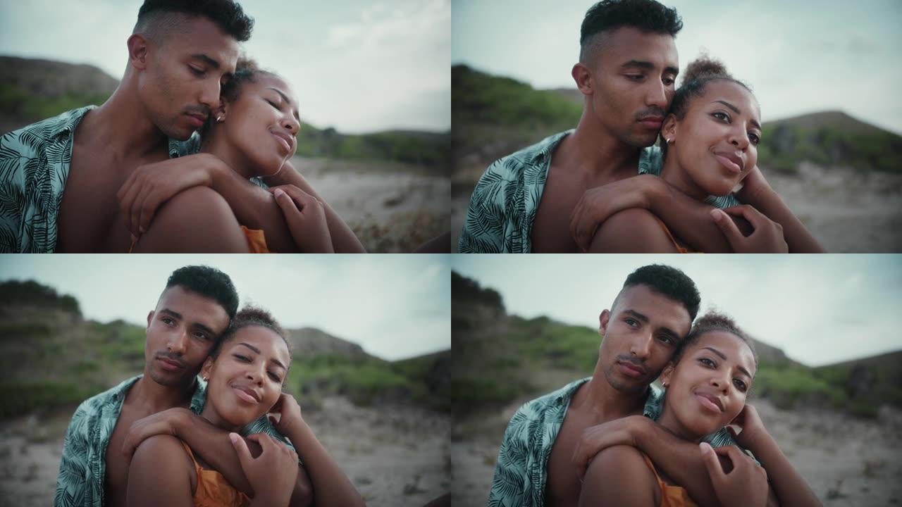 热爱非洲种族的夫妇坐在沙滩上，互相抱着。浪漫约会