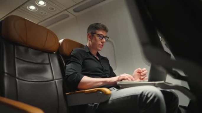 4k高加索商人在飞机上旅行时在笔记本电脑上工作。