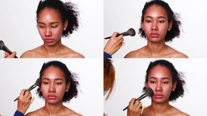 化妆师化妆非洲女性。肖像非裔美国女孩，干净健康的皮肤和非洲发型微笑孤立在白色工作室背景。