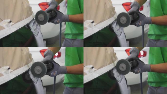 一名男子在汽车车身上使用圆形砂光机的细节照片