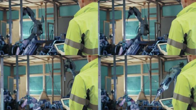 保护工作服的技术工程师在工厂中控制和指导在工业机器人上工作的机械臂的维护