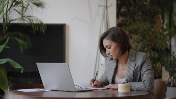 女人在家工作时使用笔记本电脑阅读短信。女人在办公室使用笔记本电脑工作学习。女商人在工作场所打字笔记本