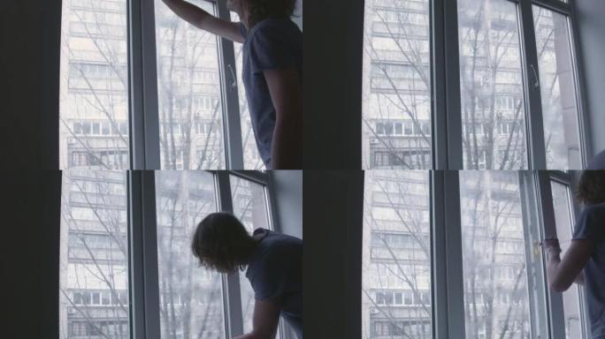 一个年轻人在厨房洗塑料窗。剪影特写。