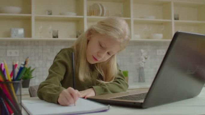 可爱的学龄聋哑女孩在笔记本电脑上学习在线课程并做作业
