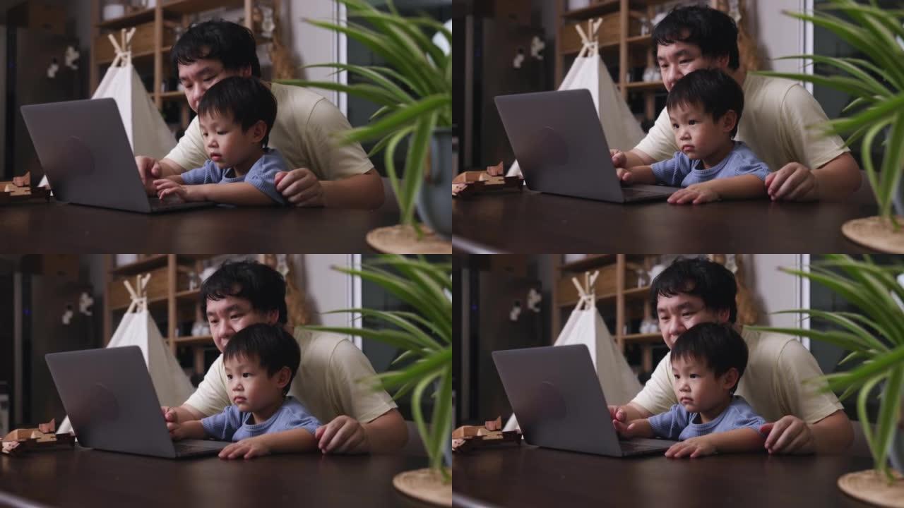 父亲抱着儿子在家时使用笔记本电脑