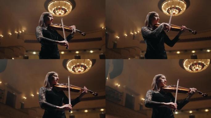 黑衣女青年在老歌剧院拉小提琴，音乐厅现场女小提琴手的肖像