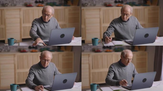 老人正在计算自己的费用和计划预算，坐在家里，用计算器计数并在笔记本电脑上打字