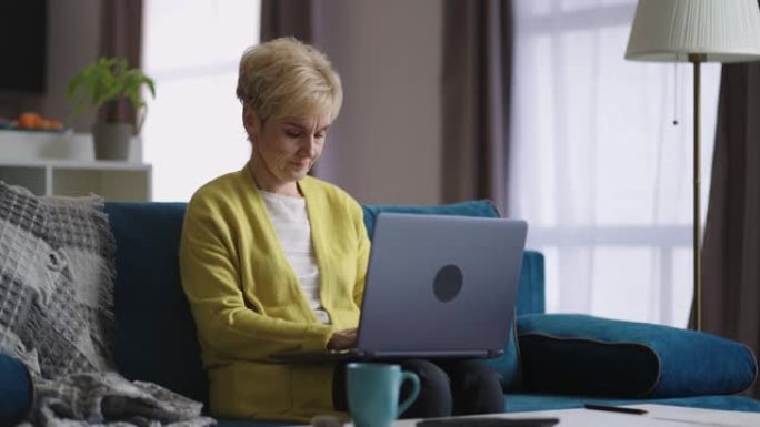 老年妇女在笔记本电脑上的在线聊天中键入和发送消息，在社交网络中进行交流，现代技术进行远程交流