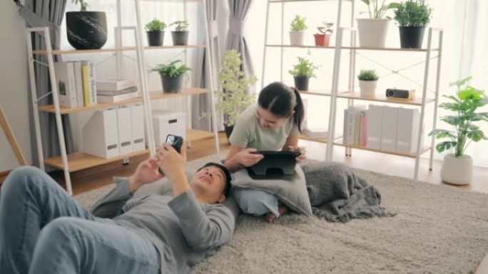 年轻夫妇在家里客厅内的在线平台上的智能手机商店观看应用程序。