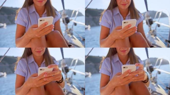 SLO MO LD女人坐在阳光下的游艇甲板上在手机上打字