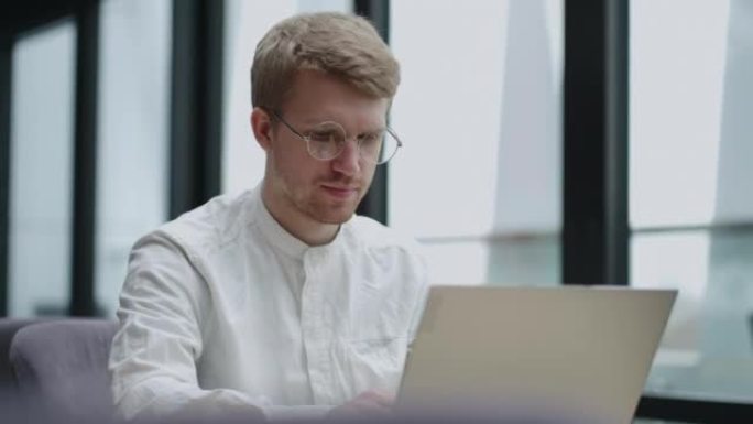 冷静的欧洲男人正在办公室或现代办公空间使用笔记本电脑，帅哥的肖像