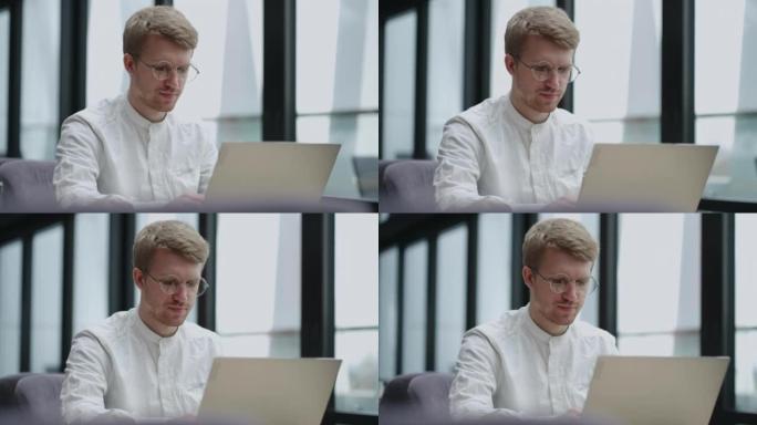 冷静的欧洲男人正在办公室或现代办公空间使用笔记本电脑，帅哥的肖像