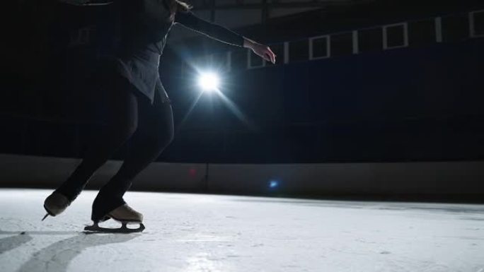 优雅的花样滑冰女子在溜冰场上滑行，用溜冰鞋在修长的腿上特写镜头，锻炼未来的冠军女子